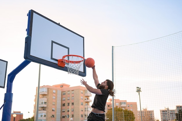 Hombre afrolatino juega baloncesto y mete la pelota en una canasta