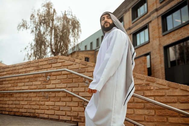 Foto un hombre afuera un hombre árabe con ropa tradicional blanca en las escaleras