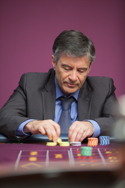 Foto hombre agarrando fichas y jugando a la ruleta