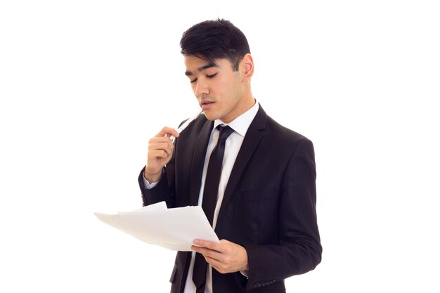 Hombre agradable con cabello negro en camisa blanca y traje negro con corbata negra con papeles