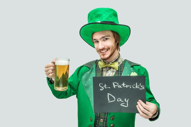 Hombre agradable joven pelirroja feliz con taza de cerveza y placa oscura en las manos.