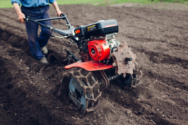 Hombre agricultor manejando un tractor pequeño para el cultivo del suelo y la siembra de papa