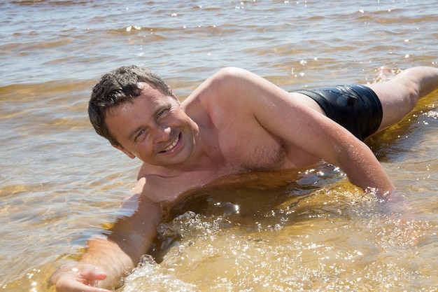 Hombre en el agua en la playa feliz de estar de vacaciones