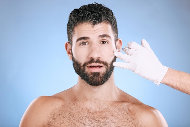 Hombre aguja y retrato para el proceso de belleza y colágeno para el cuidado de la piel en el estudio Cara sorpresa cosmética e inyección para cirugía plástica de cambio facial de botox y prp estético sobre fondo azul