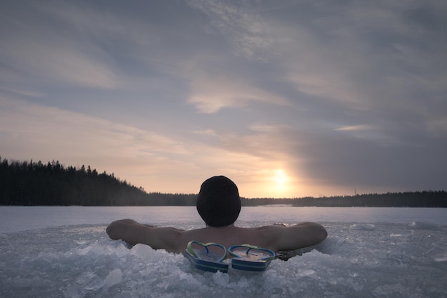 El hombre del agujero de hielo admira la puesta de sol. Vista trasera