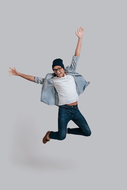 Foto hombre en el aire. longitud total de apuesto joven en camisa jeans manteniendo los brazos extendidos