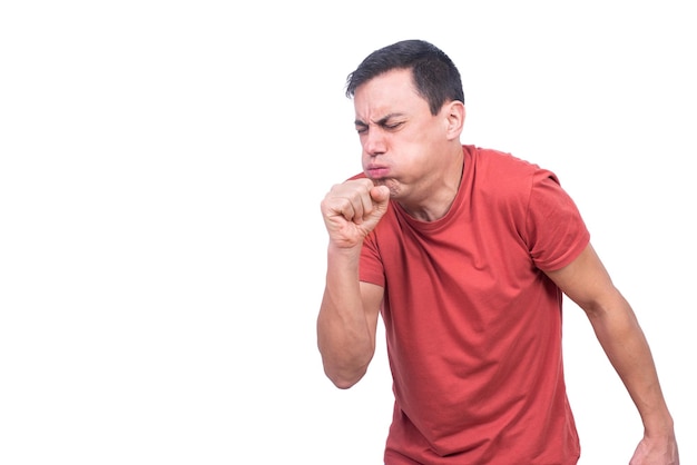 Hombre aislado en camiseta roja tosiendo con el puño cerca de la boca mientras está de pie contra un fondo en blanco