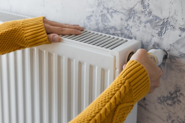 Hombre ajustando el radiador de calefacción o el calentador para instalar la temperatura de confort para la eficiencia energética y la economía en invierno