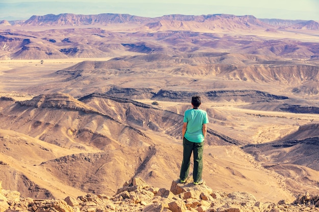 Un hombre se para al borde de un acantilado en el desierto y mira una hermosa vista