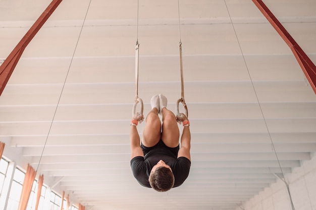 Foto hombre al revés haciendo ejercicio en anillos de gimnasia