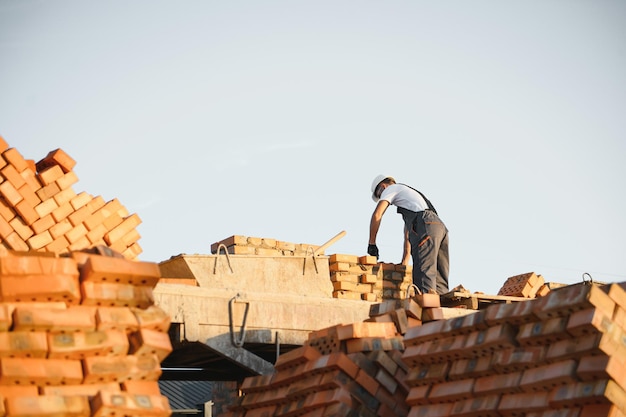 Hombre albañil instalando ladrillos en sitio en construcción