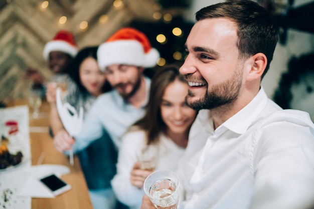 Hombre alegre con amigos borrosos en la fiesta de Navidad