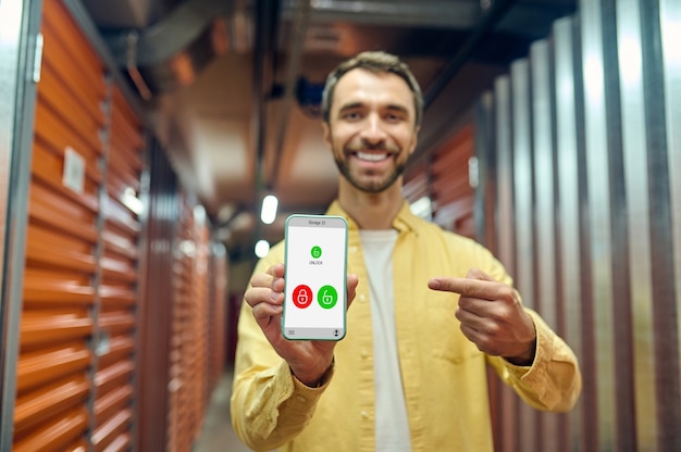 Hombre alegre apuntando con el dedo a la pantalla del teléfono inteligente