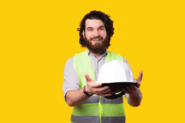 Hombre alegre arquitecto que le da un casco de protección