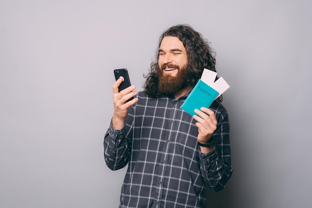 Hombre alegre con billetes de teléfono inteligente de navegación