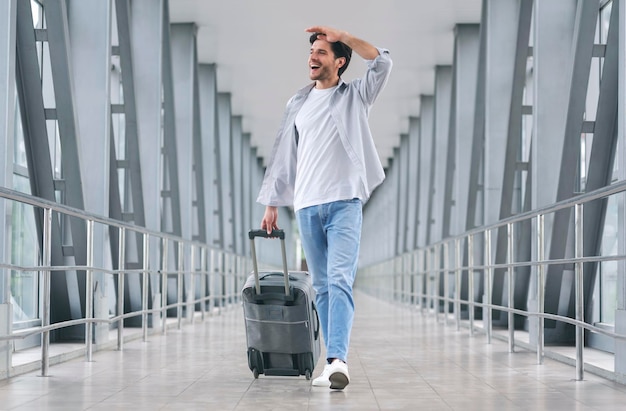 Hombre alegre caminando con equipaje en el aeropuerto