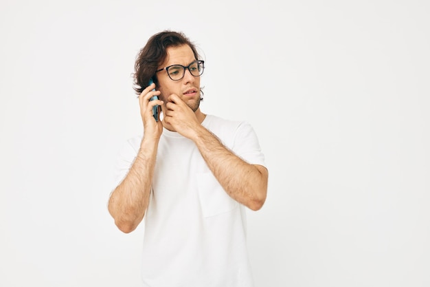 Hombre alegre en una camiseta blanca comunicación por teléfono de fondo aislado