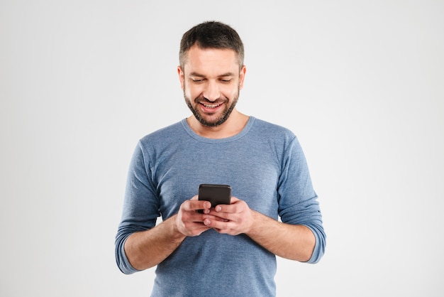 Hombre alegre chateando por teléfono móvil.