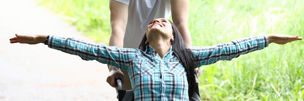 Hombre alegre conduce mujer feliz en silla de ruedas