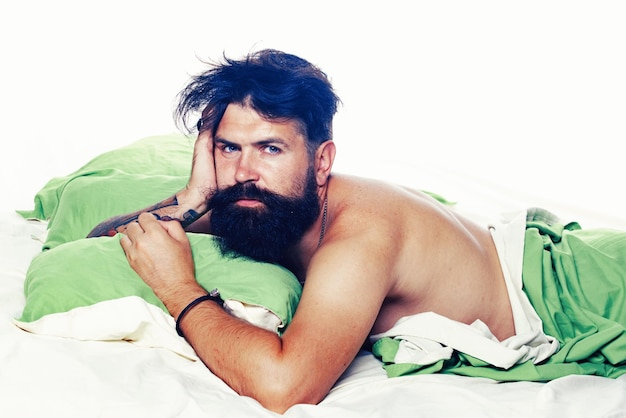 Hombre alegre durmiendo en una cama Hombre hipster barbudo que tiene problemas con el sueño Violaciones del sueño y