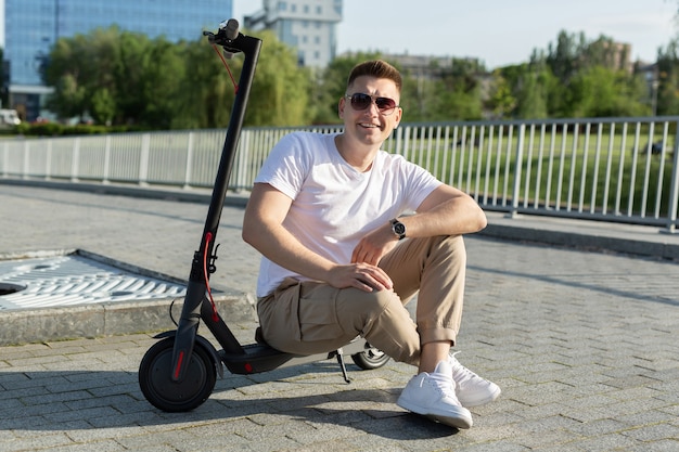 Hombre alegre está sentado en un scooter eléctrico en un parque