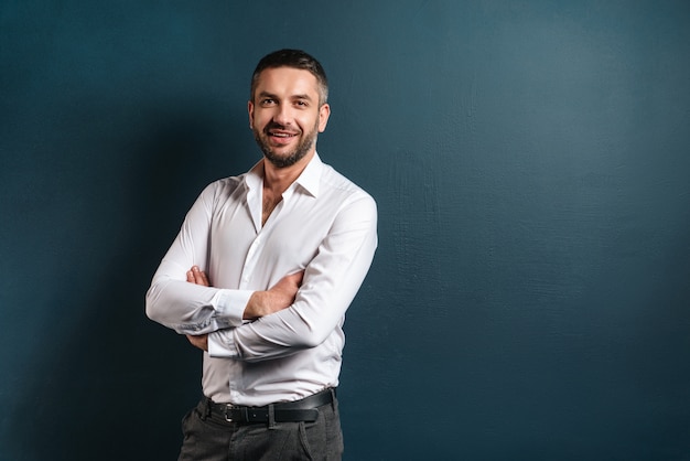 Hombre alegre guapo parado sobre la pared azul oscuro