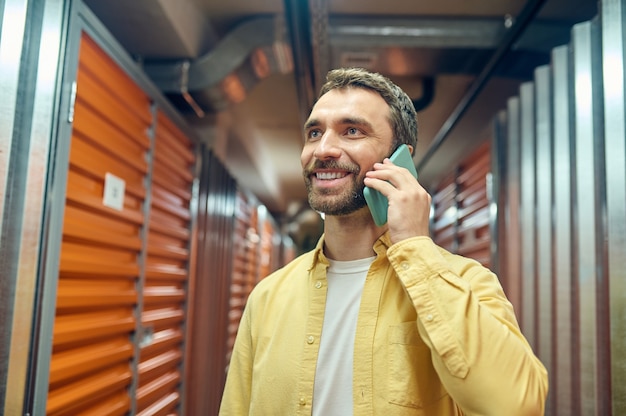 Hombre alegre hablando por teléfono inteligente cerca de contenedores