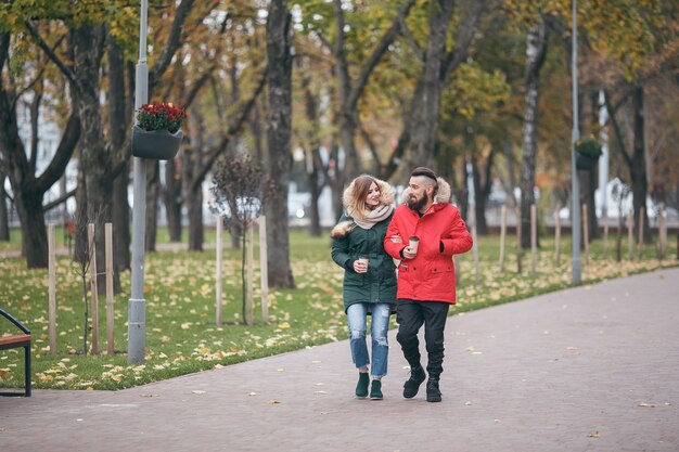 Un hombre alegre y una mujer caminan en el parque de otoño.