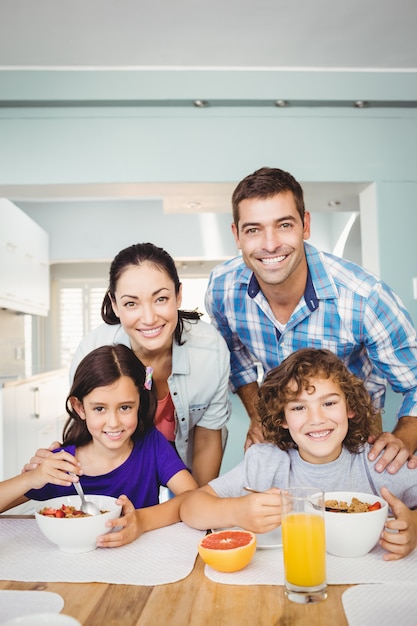 Hombre alegre y mujer con niños desayunando