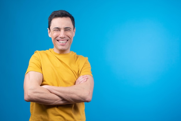 Hombre alegre de pie con los brazos cruzados y riendo en el estudio