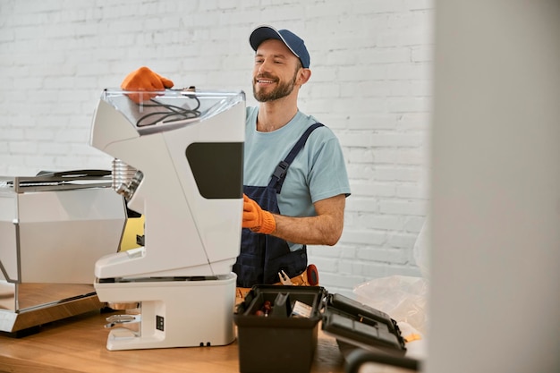 Hombre alegre que repara la máquina de café en café