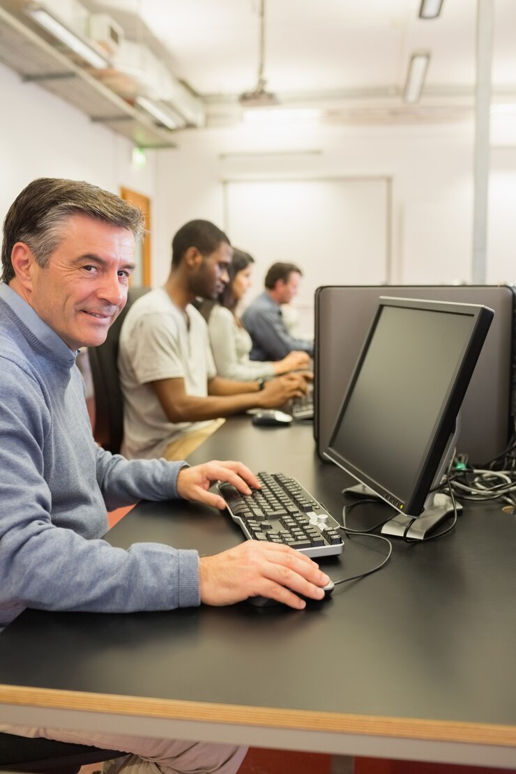 Foto hombre alegre que usa la computadora mientras que trabaja en una clase