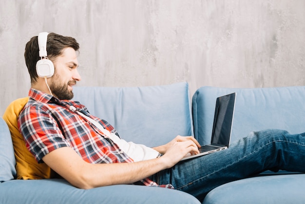 Foto hombre alegre que usa la computadora portátil y escuchando música