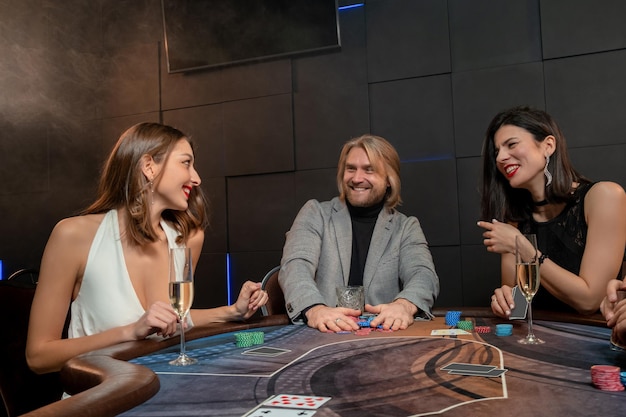 Hombre alegre recogiendo fichas después de un exitoso juego de póquer en la mesa