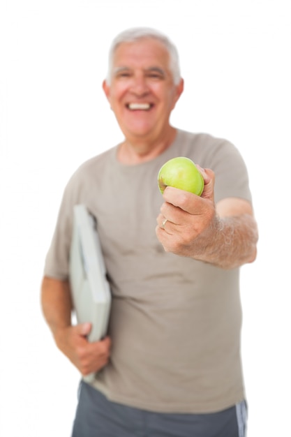 Hombre alegre senior con una manzana y escamas