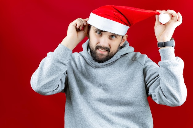 Un hombre alegre con un sombrero rojo de Santa Claus sostiene un estabilizador electrónico en su mano en el que el teléfono de un hombre toma un selfie