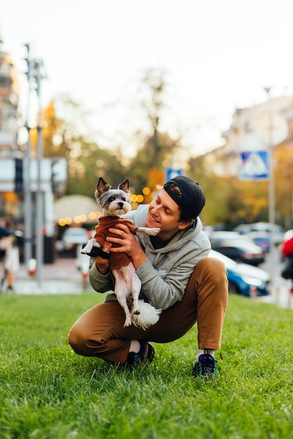 Un hombre alegre y sonriente con ropa informal se siente feliz cuando sostiene a su adorable perro york terrier