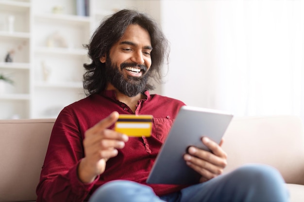 Hombre alegre con tableta y tarjeta de crédito