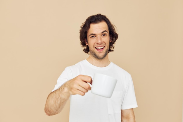 Hombre alegre con una taza blanca en sus manos emociones posando fondo beige