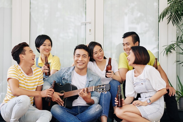 Hombre alegre tocando la guitarra para amigos