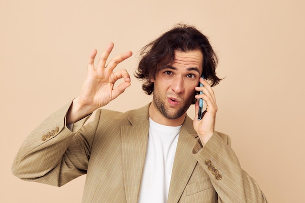 Foto hombre alegre en un traje posando emociones hablando por teléfono fondo beige