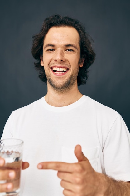 Hombre alegre vaso de agua en sus manos emociones posando fondo beige