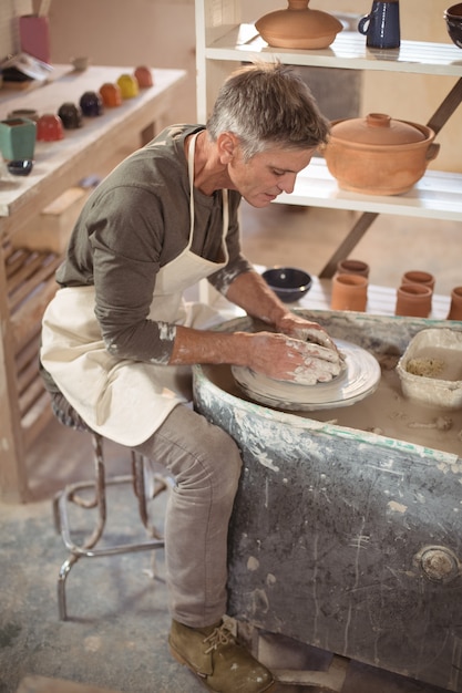 Hombre alfarero haciendo olla en taller de cerámica