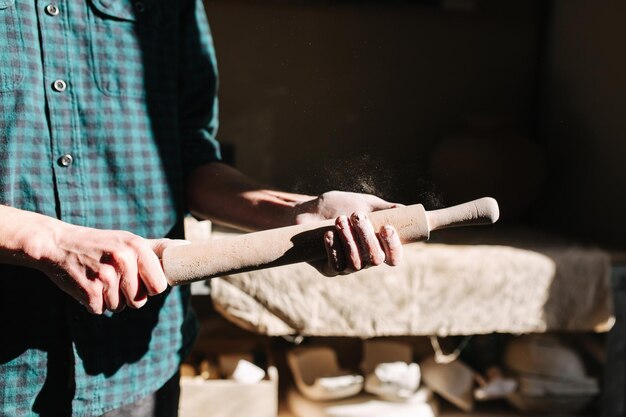 Foto hombre alfarero usa rodillo para arcilla hombre en taller