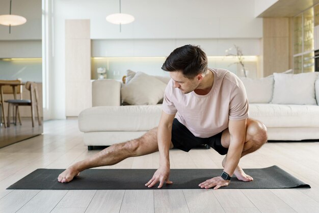 Un hombre en una alfombra de yoga se inclina en un estiramiento profundo mostrando flexibilidad y concentración