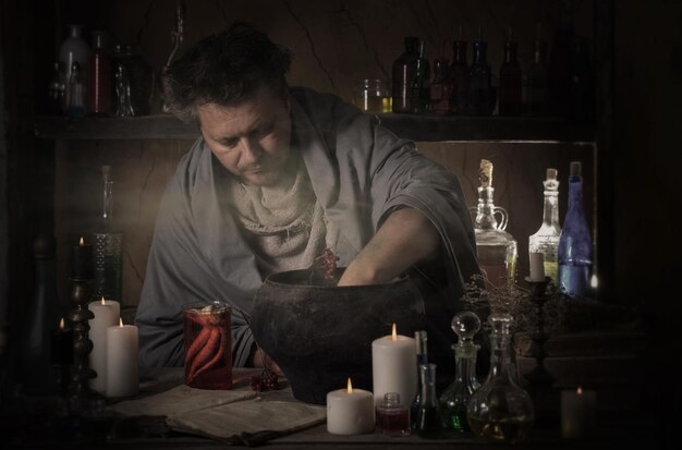 Hombre alquimista haciendo poción en cuarto oscuro