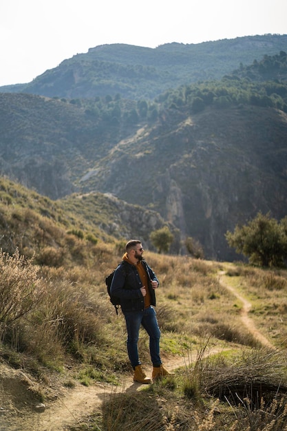 hombre alto en la naturaleza disfrutando con amigos sonriendo y divirtiéndose en el sendero de la montaña