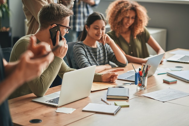 Hombre ambicioso trabajando codo a codo con mujeres jóvenes