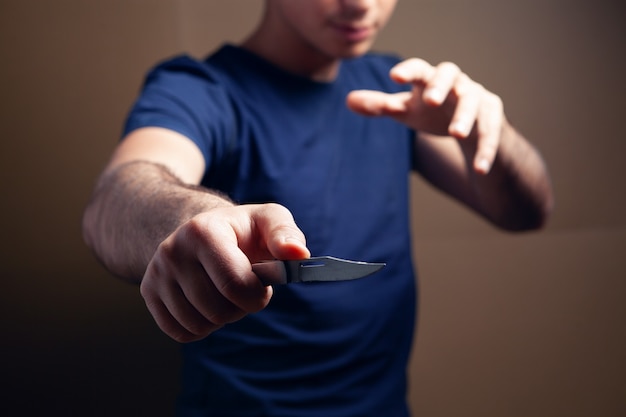 Foto el hombre amenaza con un cuchillo sobre fondo marrón