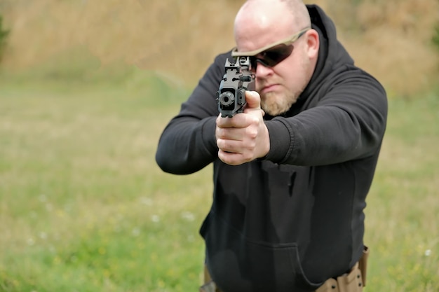 Foto un hombre amenaza con una pistola de combate que sostiene un arma en sus manos